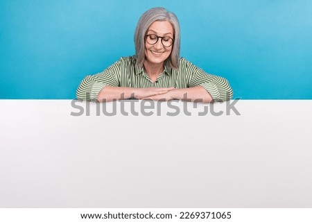 Photo of middle aged grandmother hands folded arms looking down presentation placard brand cheap online service isolated on blue color background