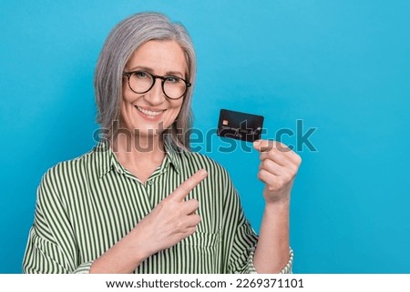 Photo of attractive cheerful lady indicate finger hand hold debit card isolated on blue color background