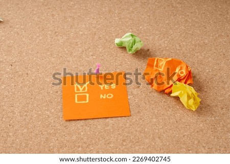 Office cork board with attached piece of paper with the words yes or no.