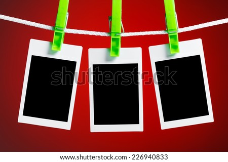 blank photos hanging on rope, red background