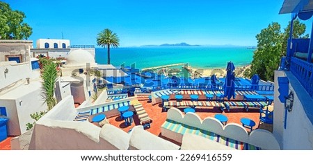 Panoramic view of scenic outdoors cafe and coastline with beach in Sidi Bou Said (blue white town). Tunisia, North Africa   Royalty-Free Stock Photo #2269416559