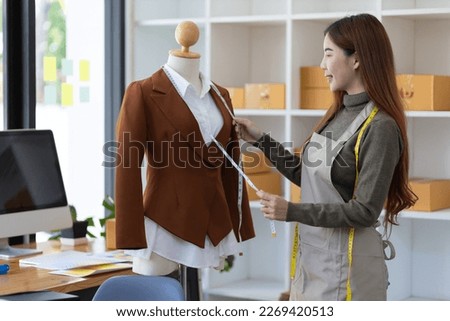Entrepreneurs start small businesses. Fashion designer working in workshop measuring shirt sample on dummy.