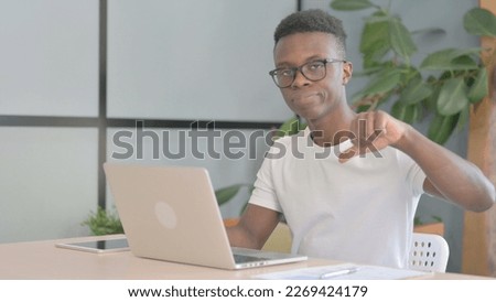Thumbs Down by Young African Man Working on Laptop