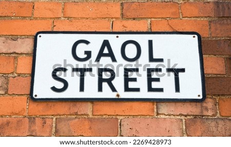 Gaol Street sign isolated against a brick wall background.