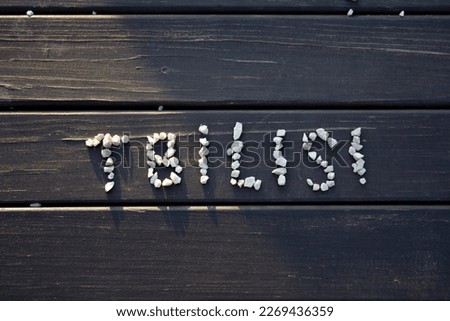 Top view. Small pebbles from the beach. The word Tbilisi is embedded from stones on the surface of a wooden bench. Concept of recreation and tourism in Georgia. Bright sunny sunny day. Text. Education