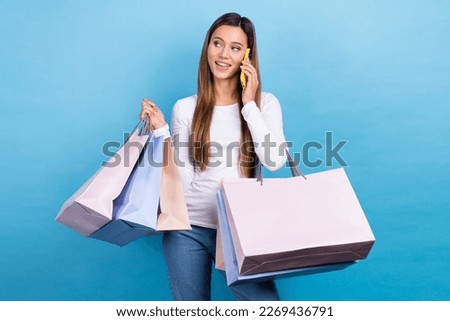 Photo of dreamy cute lady dressed white shirt holding bargains talking gadget empty space isolated blue color background