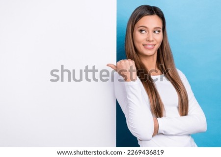 Photo of shiny cheerful lady dressed white shirt looking thumb back poster empty space isolated blue color background