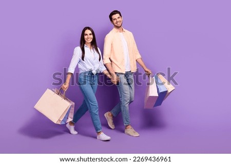 Full length photo of two cheerful lovely partners walk shopping hold arms isolated on violet color background Royalty-Free Stock Photo #2269436961