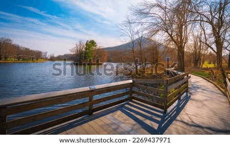Tranquil spring nature landscape of Blue Ridge Mountains and Peaks of Otter Lake on the Blue Ridge Parkway in Bedford, Virginia, USA, boardwalk footpath, green and res sprouts and water reflections