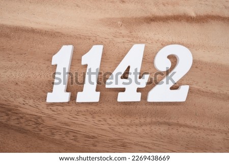 White number 1142 on a brown and light brown wooden background.