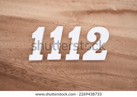 White number 1112 on a brown and light brown wooden background.
