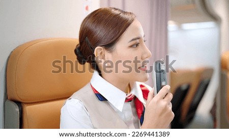 Cabin crew or air hostess flight attendants are announcing information and travel instructions on the airline via the in flight audio system Royalty-Free Stock Photo #2269441389