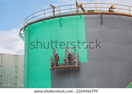 The male worker takes the cable car holding an industrial painting brush used for shell plate tank oil surface surface green color coating. Royalty-Free Stock Photo #2269446799