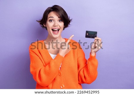 Photo of excited funny woman wear orange cardigan showing finger credit card empty space isolated violet color background
