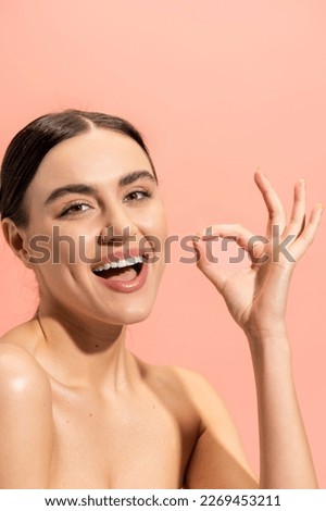 cheerful woman with opened mouth showing ok sign isolated on pink