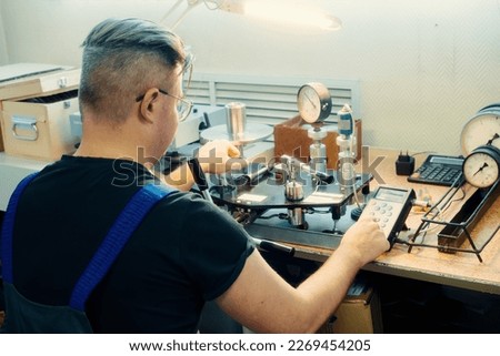 Professional calibration of pressure gauges and sensors. Working man is engaged in verification of control and measuring devices at workplace.. Royalty-Free Stock Photo #2269454205