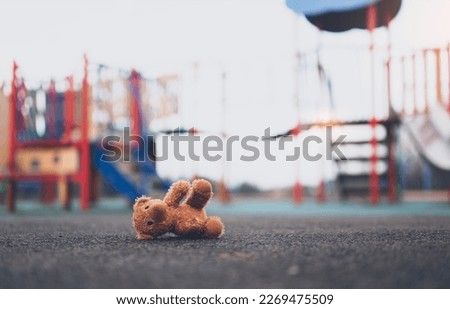 Lost teddy bear toy lying  on playground floor in gloomy day,Lonely and sad brown bear doll lied down alone in the park, Lost toy or Loneliness concept,International missing Children day Royalty-Free Stock Photo #2269475509