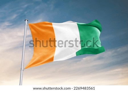 Waving flag of Ivory Coast in beautiful sky. Ivory Coast flag for independence day. The symbol of the state on wavy fabric. Royalty-Free Stock Photo #2269483561