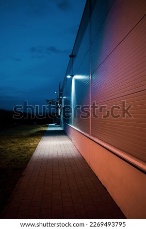 Illuminated industrial building in the evening Pavement and grass.