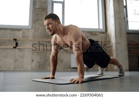 Young athletic man doing push-ups physical workout in gym Royalty-Free Stock Photo #2269504061