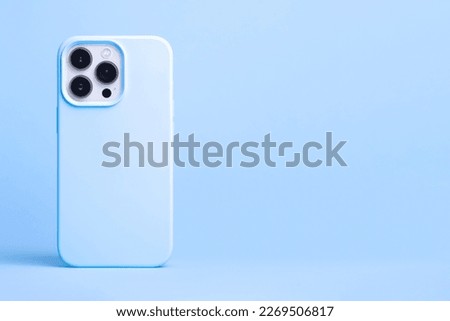 iPhone 13 and 14 Pro Max in light blue case back view isolated on blue background, phone cover mock up in monochrome colours, banner with place for text on the right