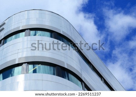 The view  on the part of the modern office building with round corner and windows and blue sky on the background