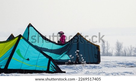 A girl in a pink jumpsuit stands behind tents in snowy winter terrain