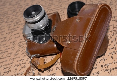 On a coffee background is an old camera with a lens and a notepad