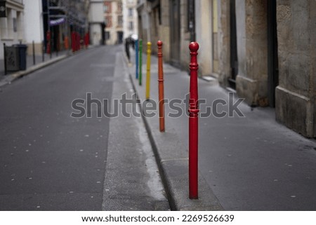 Rainbow colored painted bollards metal posts on the sidewalk near edge of street in red, orange, yellow, green and blue on a Paris road in france