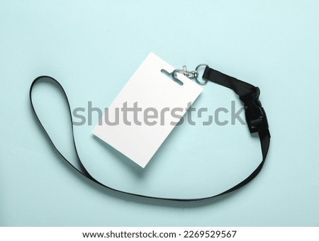 Empty white ID card badge mockup with black belt on blue background. Staff identity name tag. Space for text and design. Top view. Flat lay
