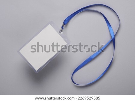 Empty white ID card badge mockup with blue belt on gray background. Staff identity name tag. Space for text and design. Top view. Flat lay Royalty-Free Stock Photo #2269529585