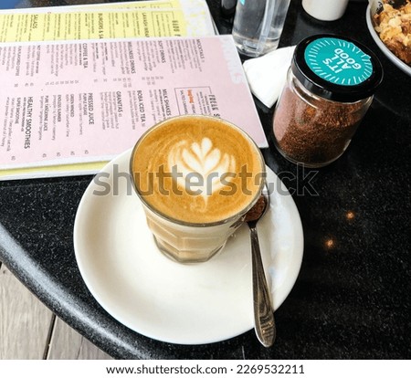 hot cappuccino on a black table, and a restaurant menu book