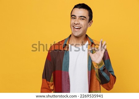 Young satisfied smiling happy fun cheerful middle eastern man 20s wear casual shirt white t-shirt showing okay ok gesture isolated on plain yellow background studio portrait People lifestyle concept