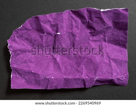 Crumpled purple torn paper piece isolated on a black background. Ripped paper sheet.
