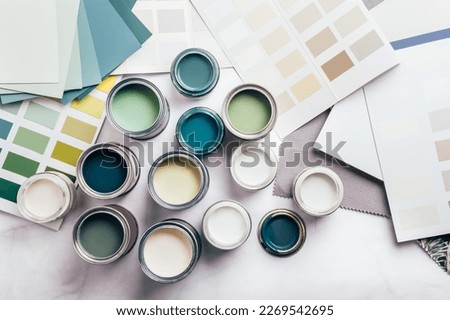 Tiny sample paint cans during house renovation, process of choosing paint for the walls, different green and beige colors, color charts on background Royalty-Free Stock Photo #2269542695