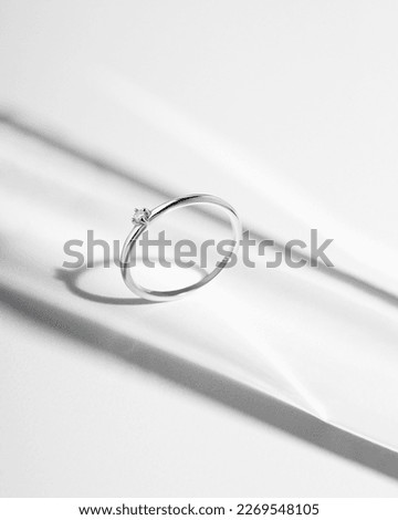 White gold ring. Silver ring with diamond on white background with shadows. Still life and creative photo