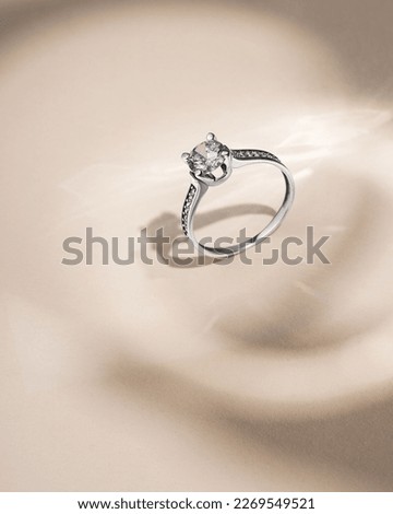 White gold ring with diamond on beige background with shadows. Still life and creative photo Royalty-Free Stock Photo #2269549521