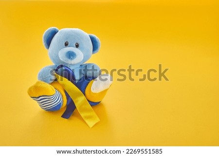 World Down Syndrome day background.Teddy bear with different socks on yellow background. Royalty-Free Stock Photo #2269551585