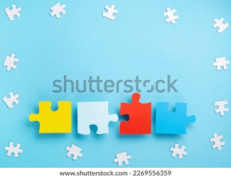 World Autism Awareness Day or month concept. Creative design for April 2. White and colorful puzzles, symbol of awareness for autism spectrum disorder on blue background. Top view, copy space.