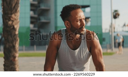 Young bearded male athlete is resting after training sitting on bench on modern background