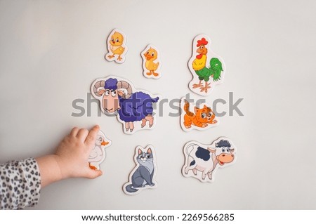 The child's hand reaches for the magnets with the image of animals