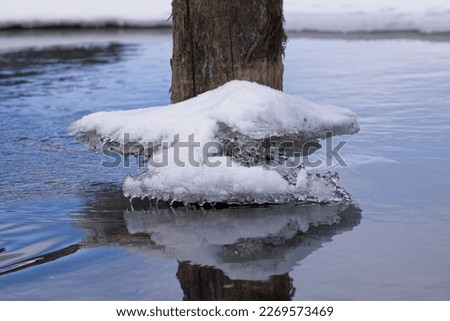 A close up photo of melting ice on a wood piling in north Idaho in late February.