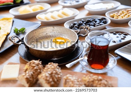 Traditional Turkish breakfast with fried eggs in copper pan and tea. Morning day with healthy nutritional value.