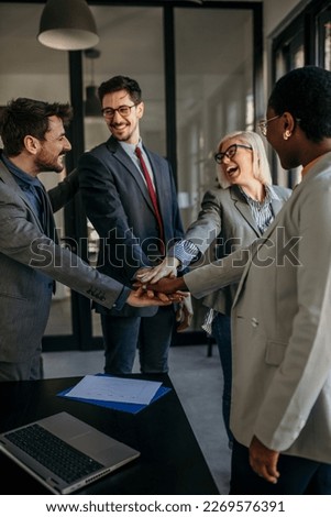 Happy diverse colleagues team people give hands on hands.  Business teamwork results are motivated by business success victory loyalty unity concept, good corporate relations, and team building.