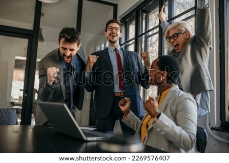 Shot of a group of young businesspeople using a laptop and celebrating in a modern office.