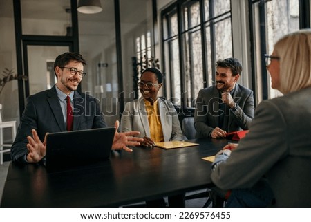 A black woman accompanied by two men sitting in the board room and having a business interview with a new candidate. Manager talking with a candidate