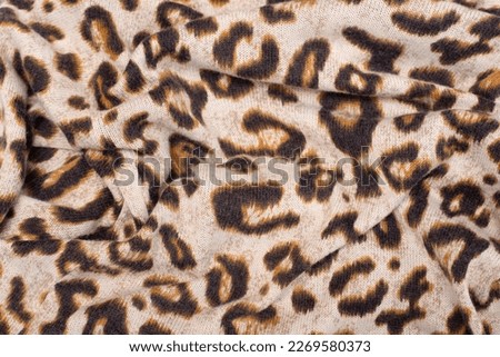Wavy fabric with the image of the skin of a wild predator, leopard or cheetah, close-up. Leopard print