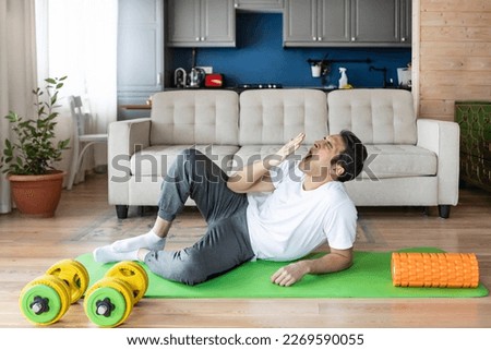 Tired young man yawning while training on the floor at home. Do sport and exercise at the morning time concept