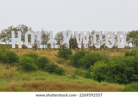 Hollywood inscription on a green hill in cloudy weather.