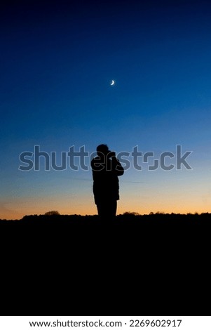 Capturing the beauty of the moment
The silhouette of a photographer taking a shot of the sunset and crescent moon creates a mesmerizing image.